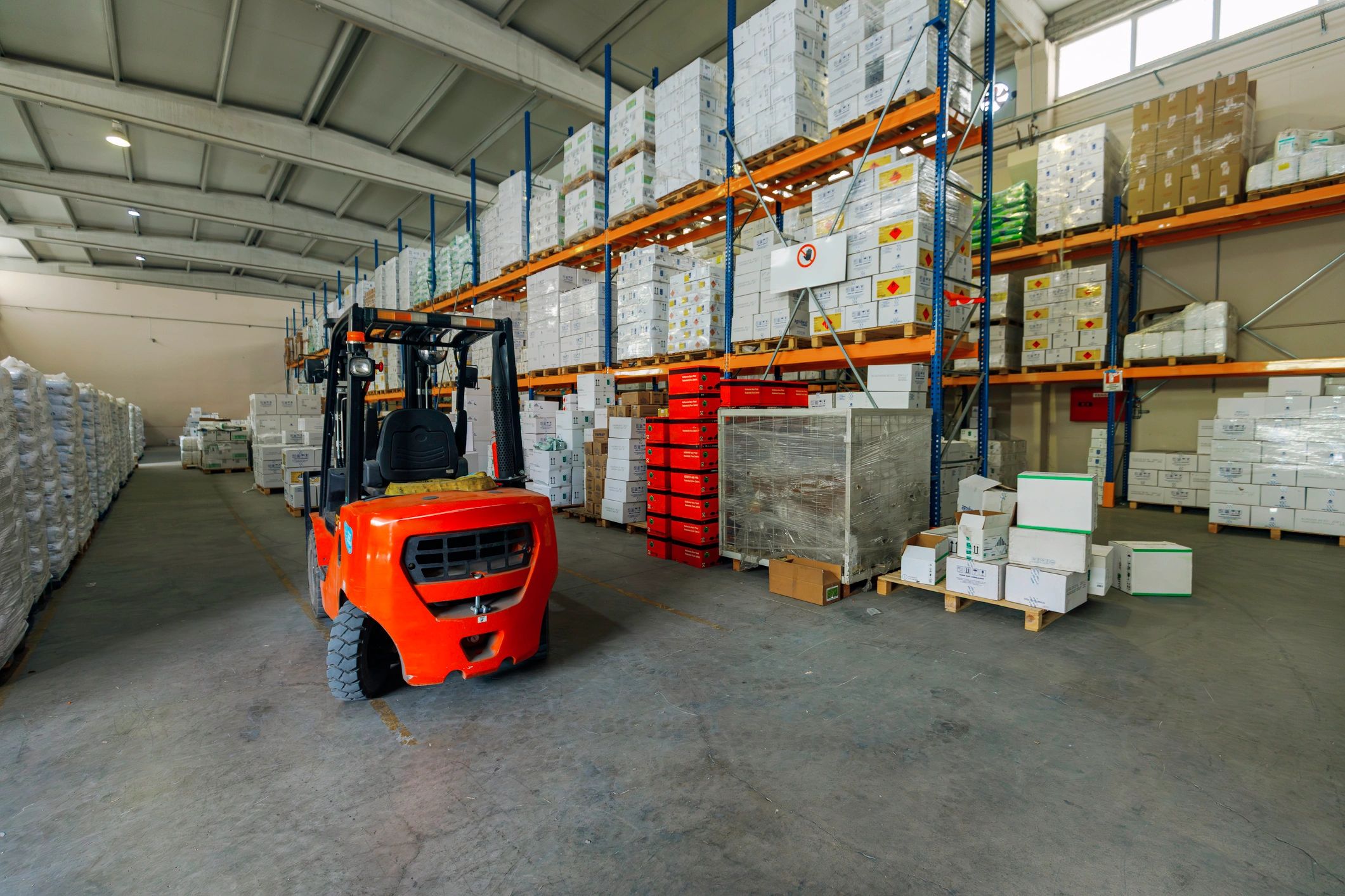 Warehouse aisle with forklift and palletized goods